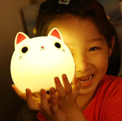 a girl smiles and holds Friendly Kitty Night Light